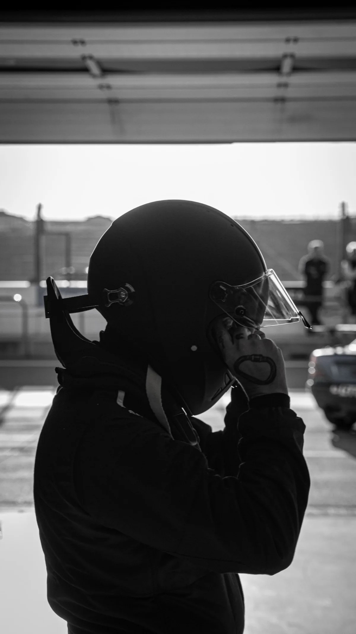 Alex met zijn helm op, in tegenlicht, in de pitstraat van Circuit Zandvoort